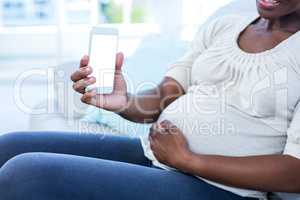 Mid section of pregnant woman showing mobile phone