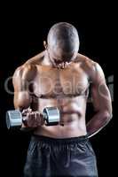 Muscular athlete looking down while exercising with dumbbell