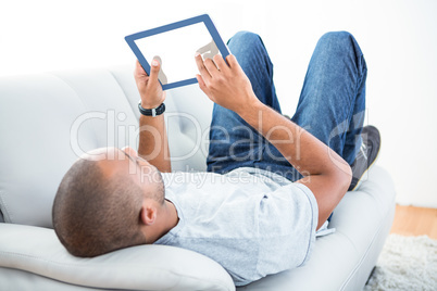 Young man using tablet computer on sofa