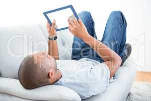 Young man using tablet computer on sofa