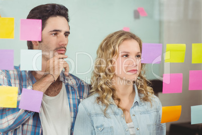 Colleagues looking at notes on glass in office