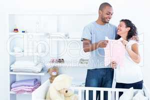 Cheerful couple holding baby clothing