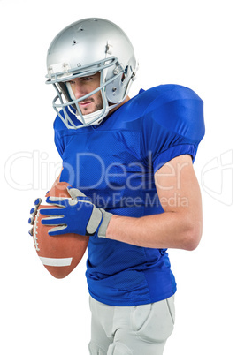 American football player holding ball while looking away