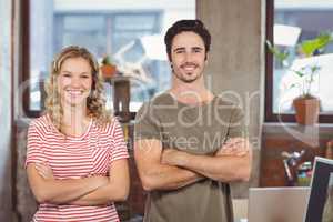 Portrait of smiling man and woman with arms crossed standing in