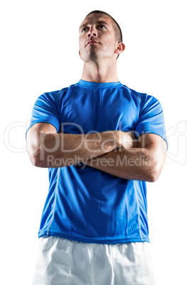 Serious rugby player looking away with arms crossed