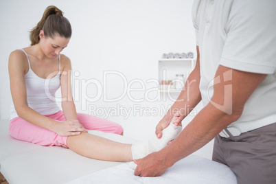 Doctor bandaging his patient ankle