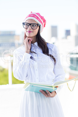 Thoughtful woman with finger on cheek holding documents