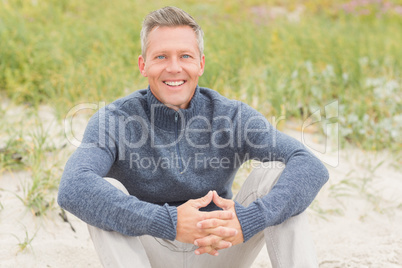 Smiling man sitting on the sand