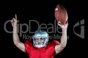 American football player with arms raised holding ball