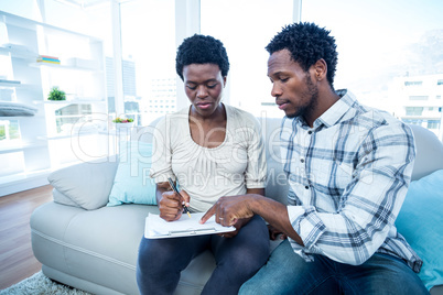 Man pointing on notepad while talking with pregnant wife