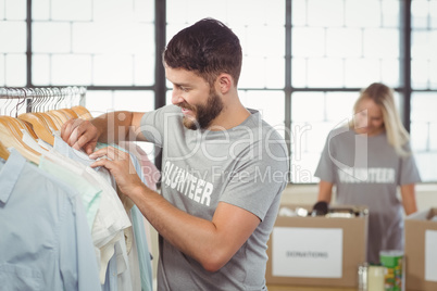 Happy man choosing clothes for donation