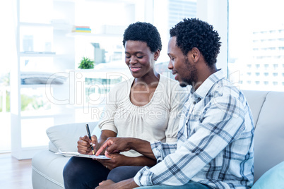 Happy man talking with pregnant wife while pointing on paper