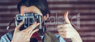 Man showing thumbs up gesture while photographing