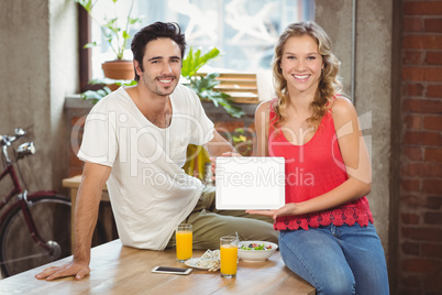 Smiling business people showing digital tablet in office