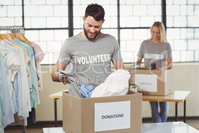 Smiling man separating clothes from donation box