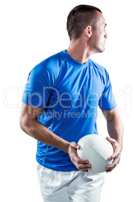 Rugby player looking away while holding ball aside