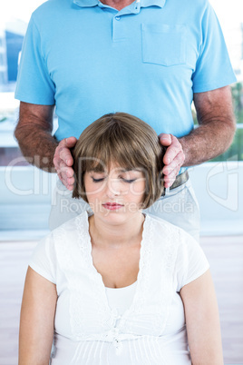 Therapist performing reiki over woman