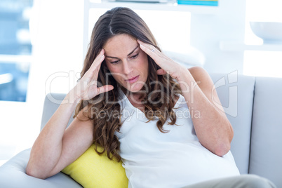 Depressed pregnant woman sitting on sofa