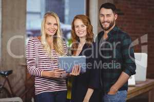 Portrait of smiling colleagues holding digital tablet