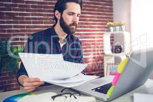 Creative businessman with documents using laptop