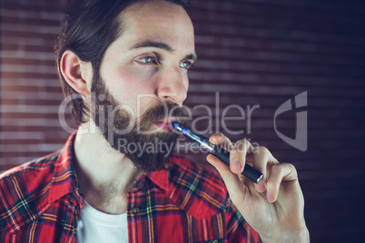 Confident hipster smoking electronic cigarette