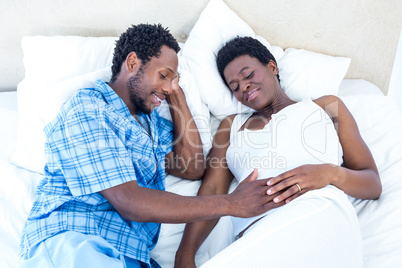High angle view of husband and wife relaxing on bed