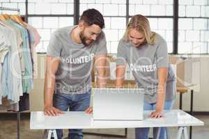 Volunteers discussing while working on laptop in office