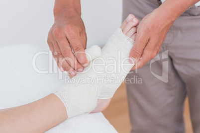 Doctor bandaging his patient ankle