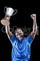 Portrait of happy sportsman cheering while holding trophy