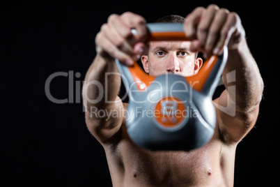 Confident shirtless athlete showing kettlebell