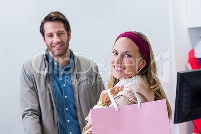 Smiling woman with shopping bag in front of cashier