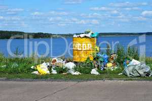 Overflowing barrel with rubbish and waste disposal on the waterf