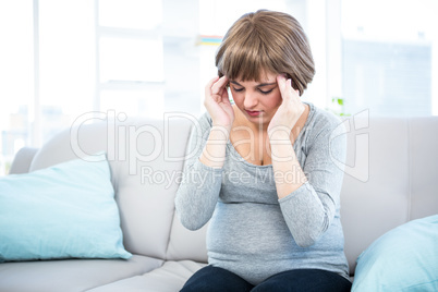 Pregnant woman having headache on couch