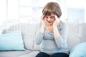 Pregnant woman having headache on couch
