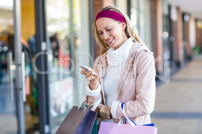 Smiling woman with shopping bags using smartphone