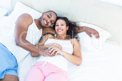 Portrait of happy pregnant wife with husband lying on bed Portrait of happy pregnant wife with husband lying on bed