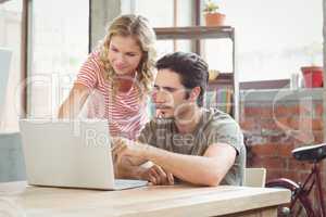 Man and woman working on laptop in office
