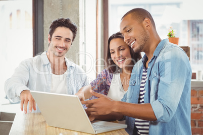 Happy business people pointing towards laptop in office