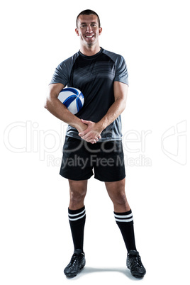 Smiling rugby player in black jersey holding ball with hands cla