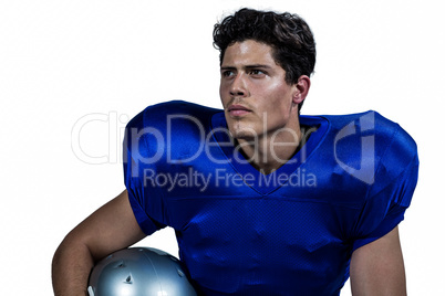 American football player holding helmet while looking away