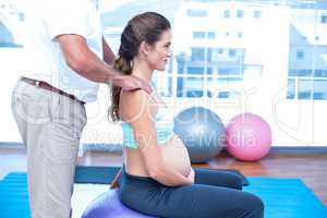 Midsection of instructor helping pregnant woman