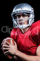 Serious American football player looking away while holding ball
