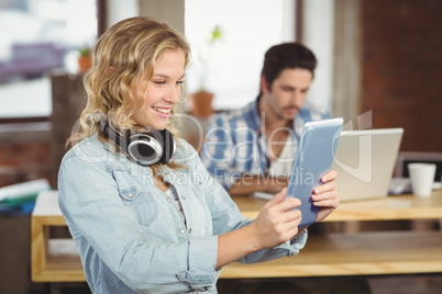 Beautiful woman smiling while looking at tablet in ofiise