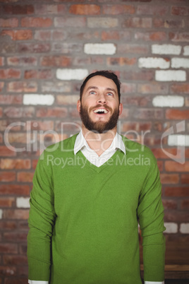 Happy businessman looking up while standing against wall