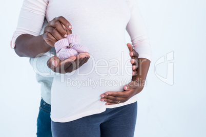 Mid section of man holding baby shoes along with wife