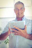 Smiling businessman holding digital tablet at office