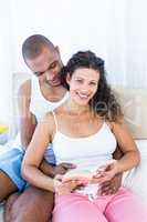 Portrait of pregnant wife holding book with husband on bed