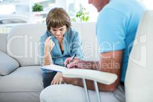 Doctor writing on notepad while consulting female patient