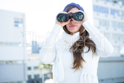 Cold brunette in warm clothes using binoculars