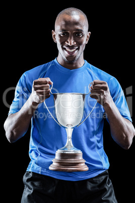 Portrait of happy sportsman holding trophy